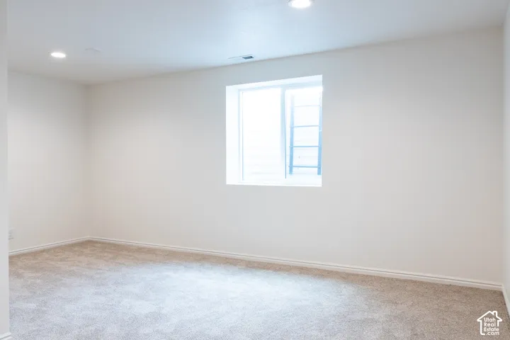 Recessed ceiling lighting, light-toned carpeting, white wall finishes, egress window, and white trim