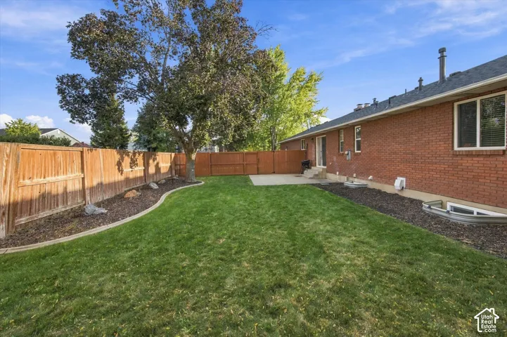 Expansive backyard featuring a manicured lawn, established landscaping, and a privacy fence