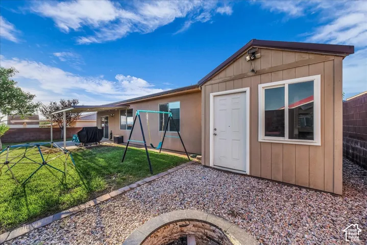Backyard featuring a detached storage shed, covered patio, gravel landscaping, and a built-in fire pit