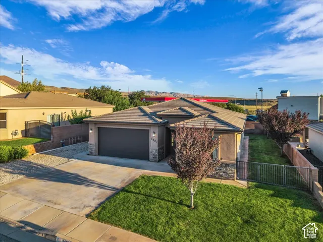 Stucco exterior with a tiled roof, attached garage, concrete driveway, and front lawn