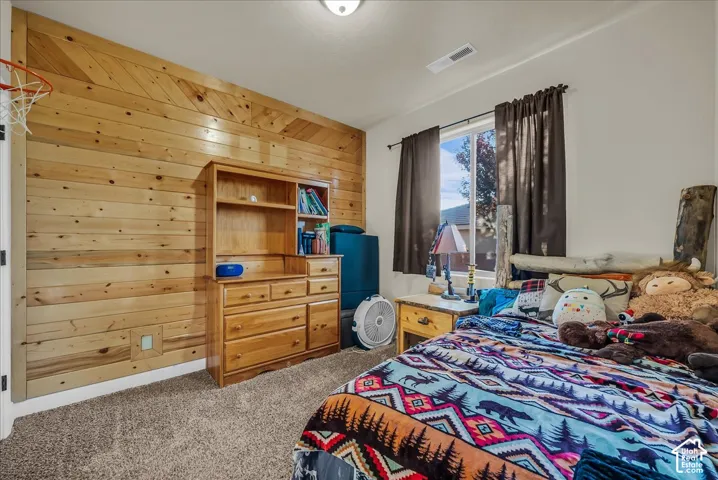 Wood-paneled accent wall, neutral carpeting, and a window with dark draperies