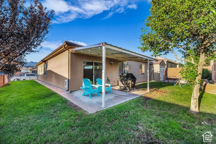 Expansive backyard featuring a covered patio, stucco exterior, mature trees, and a concrete patio