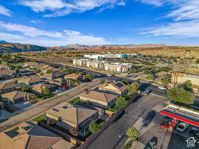 Aerial perspective showcasing an established residential neighborhood, commercial buildings, and distant mountainous terrain