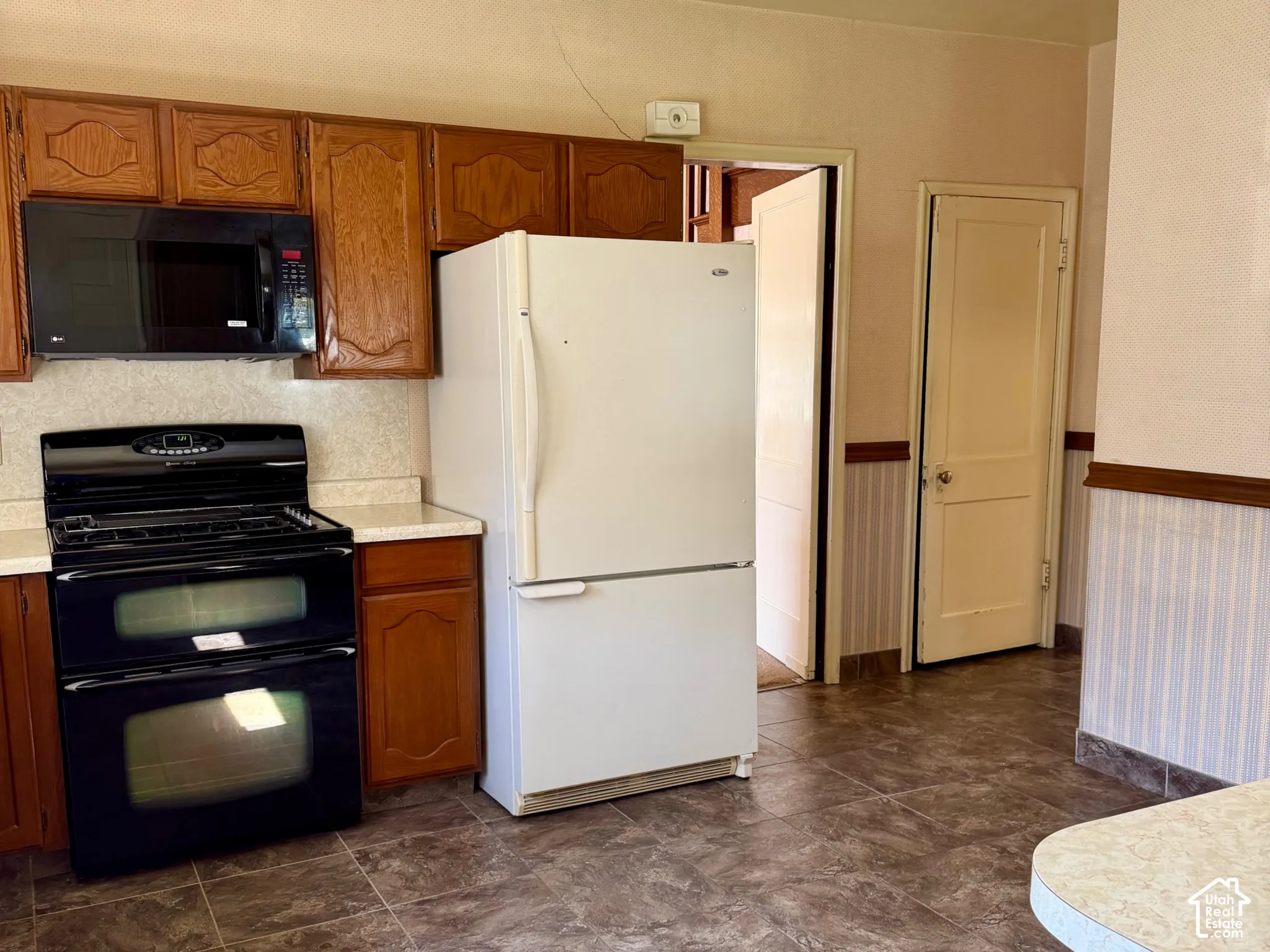 Kitchen with wood-finish cabinetry, tile flooring, and integrated appliances