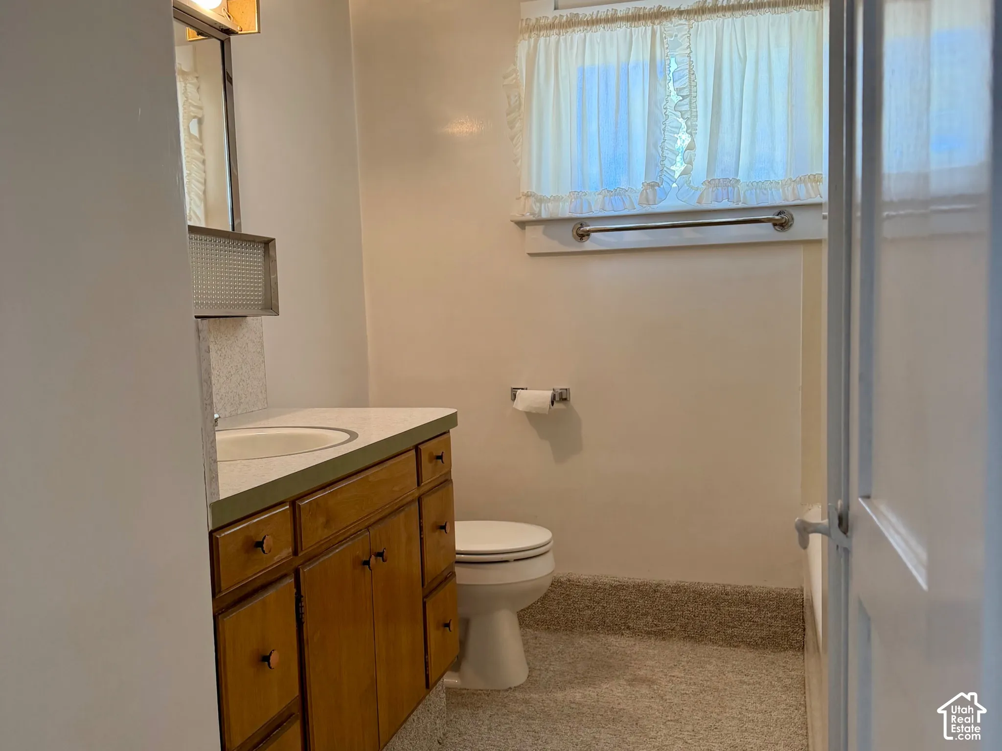 Wood-tone vanity with dual sinks, wall-mounted lighting, and a neutral-toned countertop