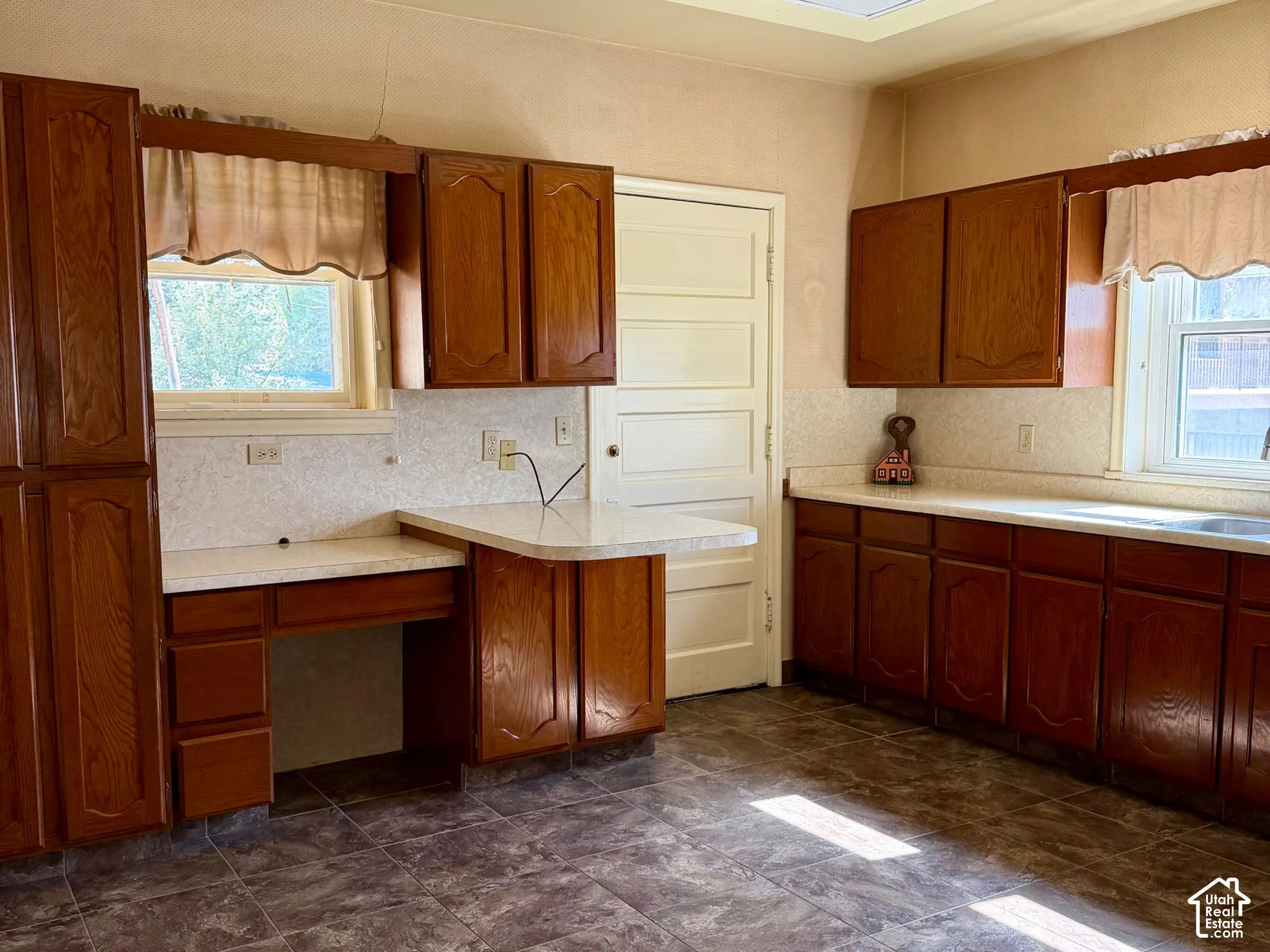 Wood-finish cabinetry with light countertops, tiled flooring, and a drop ceiling with recessed lighting