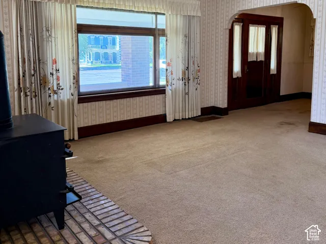 Carpeted living area with a brick fireplace hearth and a large window
