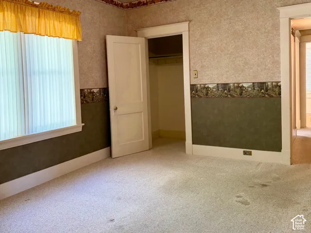 Carpeted room featuring a ceiling-mounted light fixture, a window with vertical blinds, and a built-in closet