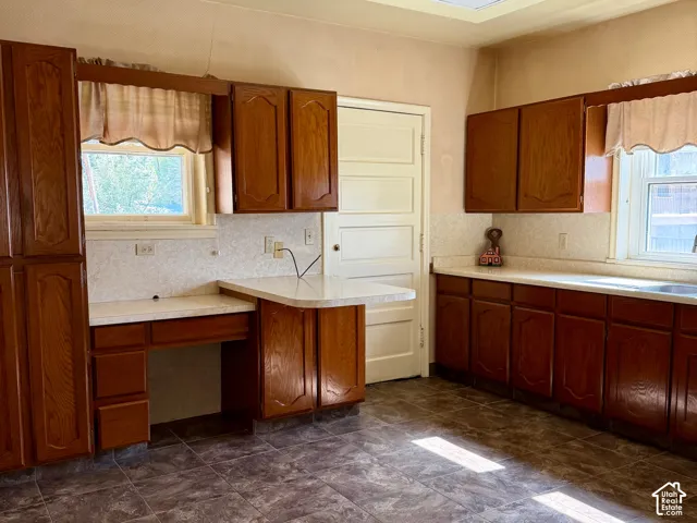 Wood-finish cabinetry with light countertops, tiled flooring, and a drop ceiling with recessed lighting