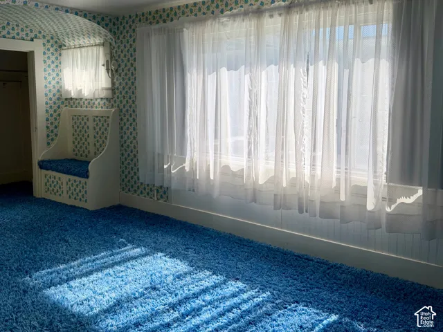 Built-in window bench with storage, overhead light fixture, floor-to-ceiling window, and patterned wallpaper border
