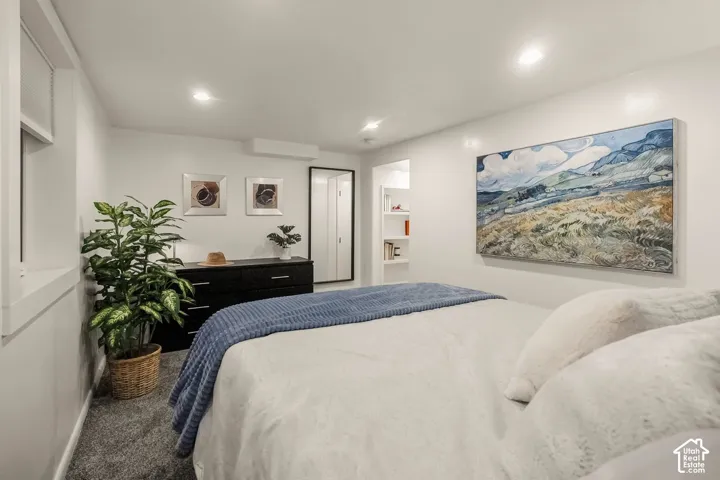 Recessed lighting, wall-mounted climate control unit, built-in shelving, window with blinds, and durable gray carpeting