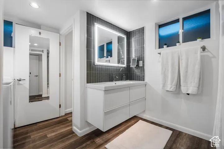 Modern primary bathroom featuring a floating vanity with dual drawers, white quartz countertop, and an illuminated framed mirror