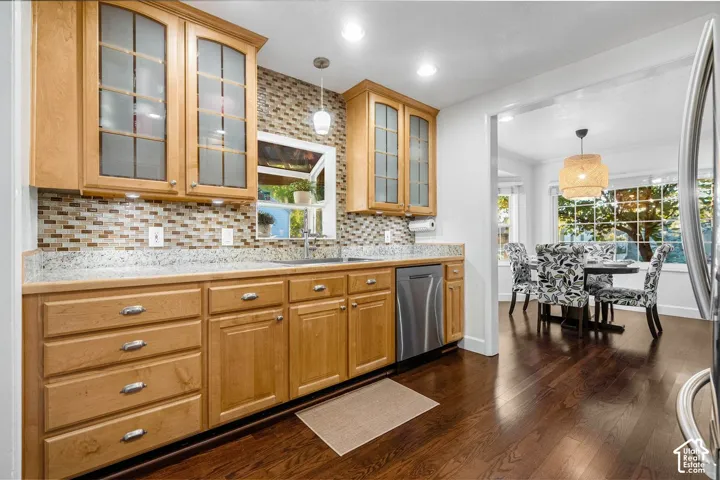 Kitchen featuring wood cabinetry, a mosaic tile backsplash, light-toned countertops, and wood-finish flooring