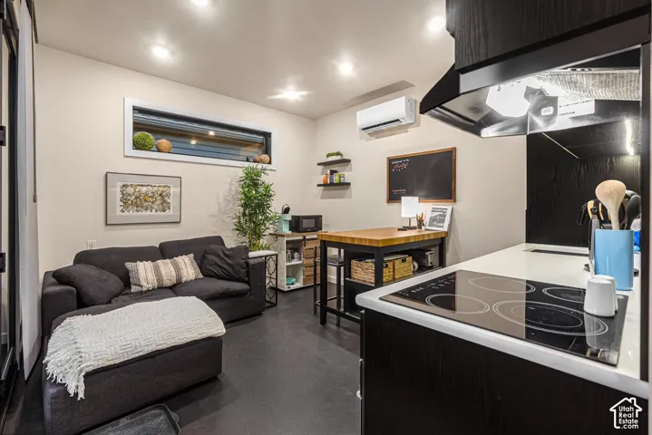Compact living area featuring recessed lighting, a horizontal clerestory window, dark wood-finish flooring, a built-in cooktop, and an overhead range hood