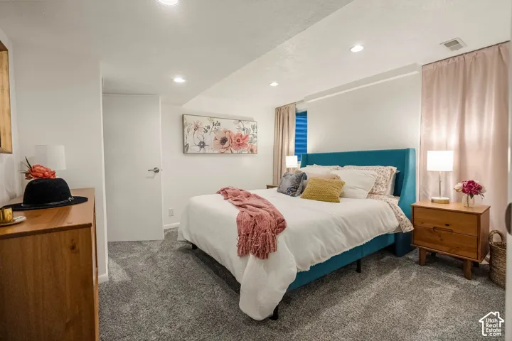 Recessed lighting illuminates the space, featuring carpeting, a solid core door, and a curtained window