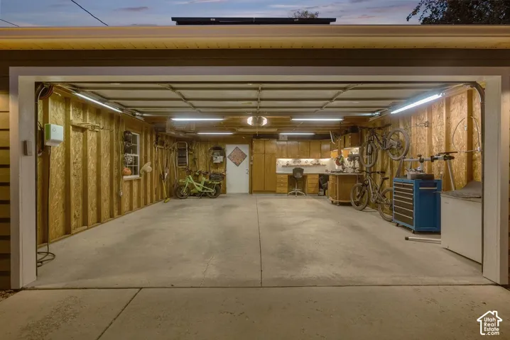 Spacious garage with concrete flooring, exposed wood-paneled walls, built-in cabinetry, and overhead lighting