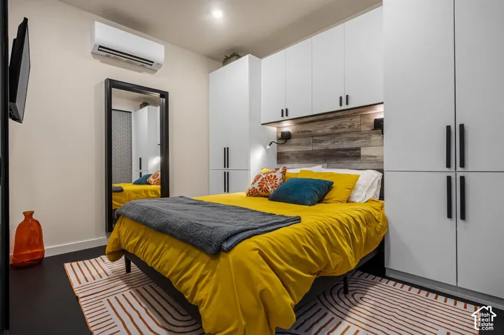 Integrated wall-mounted cabinetry, wood-finish accent wall, dark wide-plank flooring, and recessed ceiling lighting