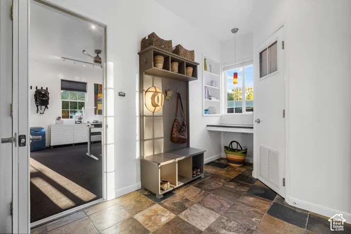 Slate tile flooring, built-in shelving, desk niche, and a window with a pendant light
