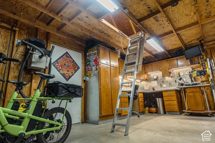 Garage workspace with wood paneling, wood-finish cabinetry, built-in shelving, and overhead fluorescent lighting