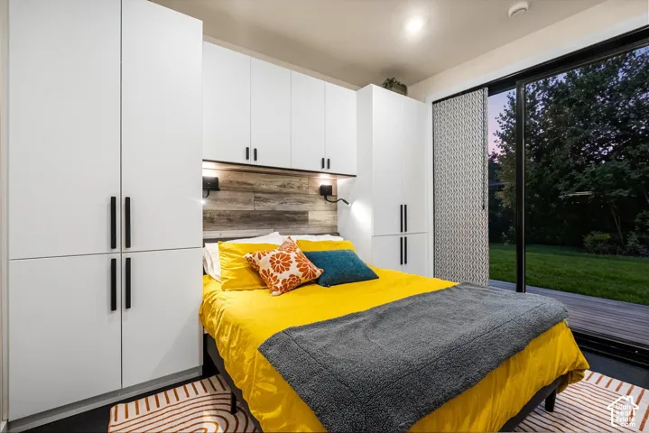 Built-in white cabinetry with black hardware, wood-finish accent wall with sconces, large sliding glass door, and exterior decking