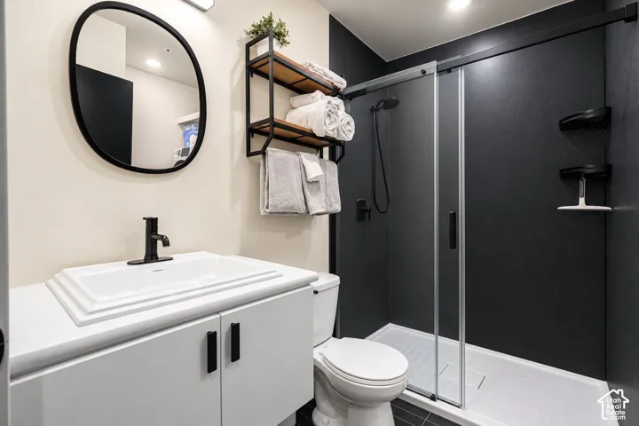 Bathroom featuring a rectangular drop-in sink with a matte black faucet, a white vanity with matte black hardware, and a walk-in shower with a sliding glass door