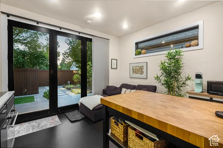 Black framed French doors leading to an outdoor area with a wood-finish deck and gravel landscaping