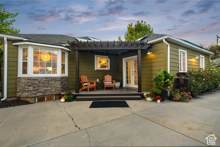Exterior featuring a bay window with stone veneer, a covered patio with a pergola, and French doors