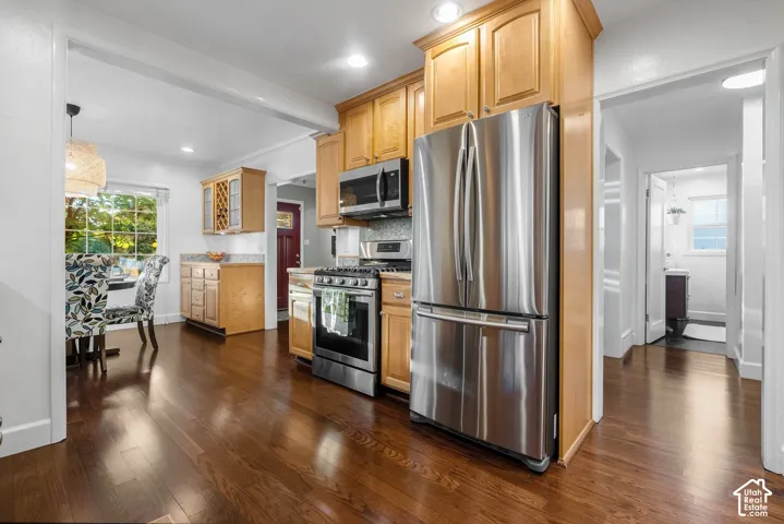 Hardwood-finish flooring, stainless steel appliances, light wood cabinetry, recessed lighting, and a kitchen window overlooking exterior greenery