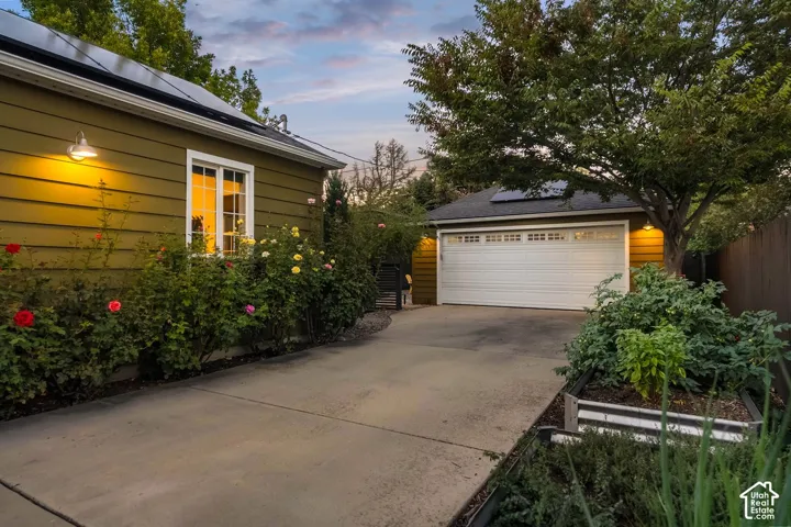 Exterior featuring horizontal siding, white-framed window, attached wall sconce, and mature landscaping