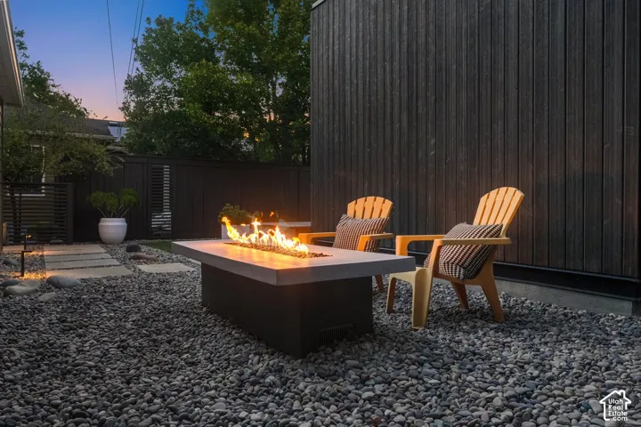 Private outdoor space featuring a rectangular fire pit, dark vertical siding, and a decorative pebble ground cover