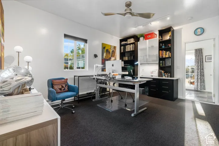 Built-in cabinetry with a light-toned countertop, track lighting, and a ceiling fan