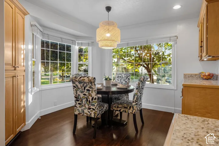 Bay window with multiple panes, wood-finish flooring, built-in wooden cabinetry, light-colored countertops, and a decorative overhead light fixture