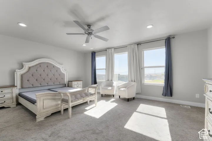 Recessed lighting, ceiling fan, three windows with natural light, and carpeted flooring