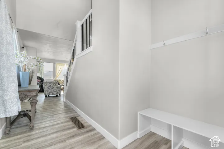 Entryway featuring a built-in bench, wall-mounted coat rack, and wood-finish flooring