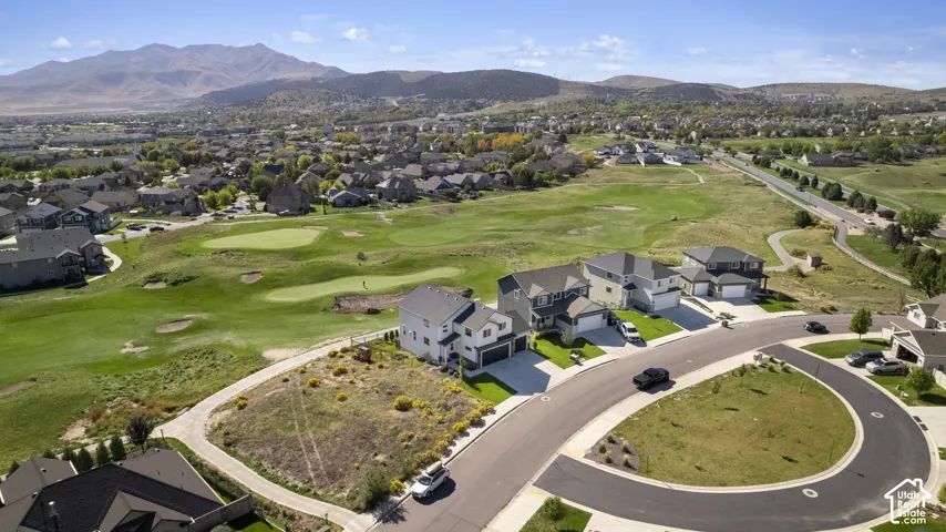 Residential properties situated along a golf course, featuring paved roads and mountain scenery