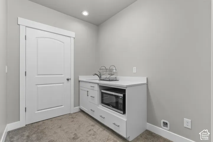 Built-in cabinetry with a sink and microwave, light-colored walls, and recessed lighting