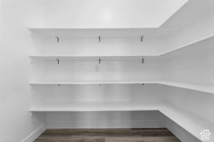 Built-in white shelving providing extensive storage, complemented by wood-finish flooring
