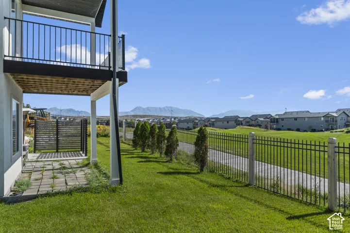 Expansive green space featuring a black metal fence, mature trees, and a mountain backdrop