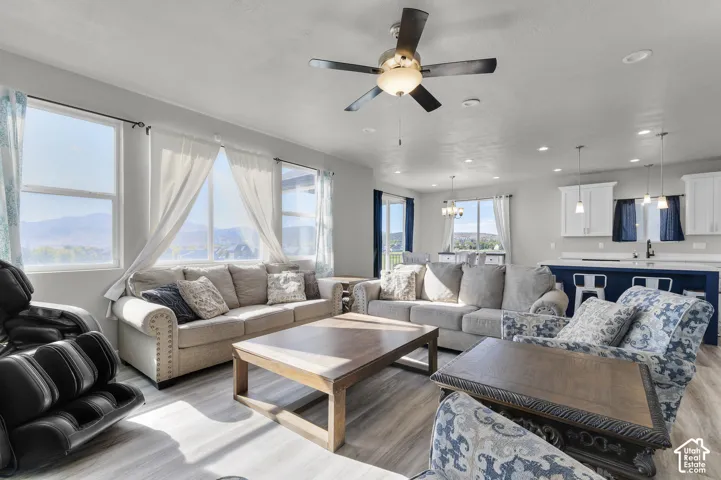 Open-concept living area with wood-finish flooring, a ceiling fan, and large windows
