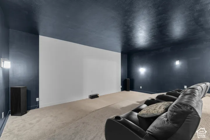 Expansive projection wall, dark-toned walls and ceiling, wall-mounted sconce lighting, and light-toned carpeting