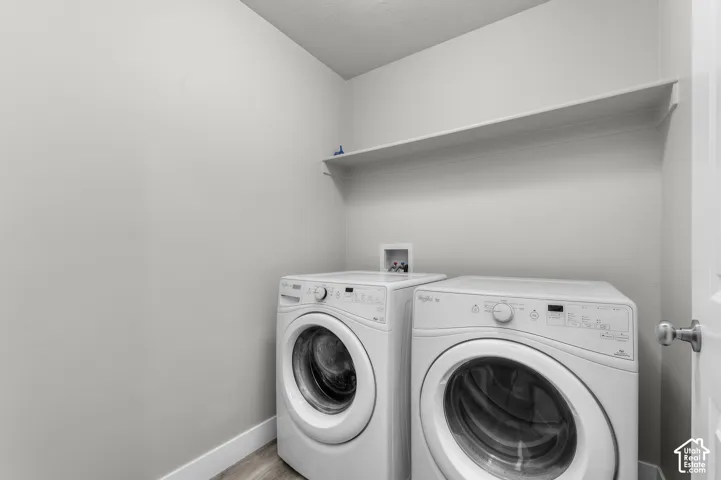 Laundry area with wood-finish flooring and integrated wall shelving