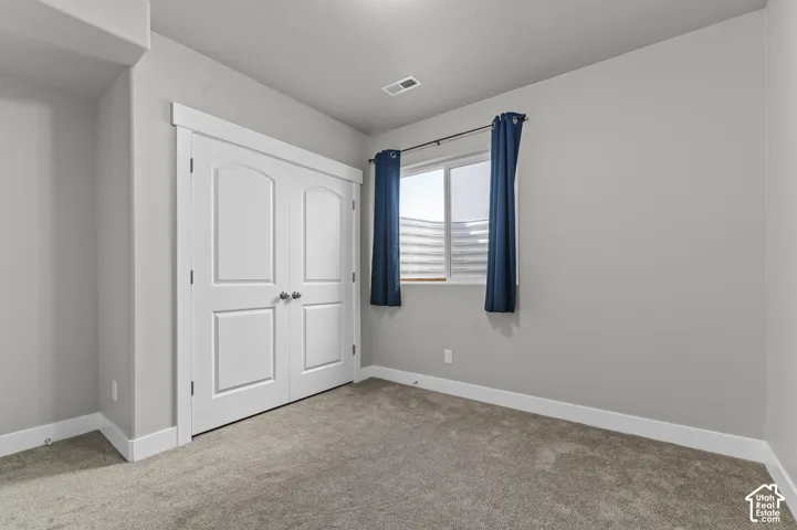 Neutral gray wall paint, recessed ceiling lighting, light gray carpeting, double arched panel doors, and a window with white trim