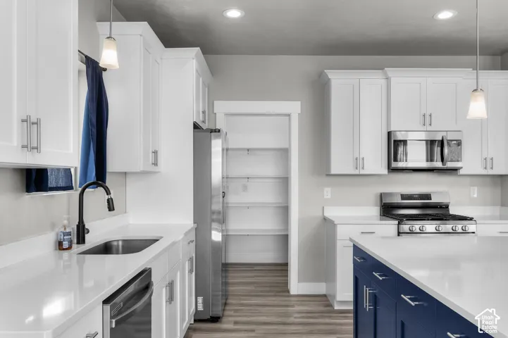 White shaker cabinetry with modern pulls, white countertops, stainless steel appliances, and wood-finish flooring