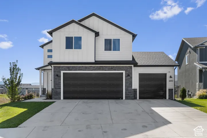 Contemporary two-story exterior with white vertical siding and dark stone accents