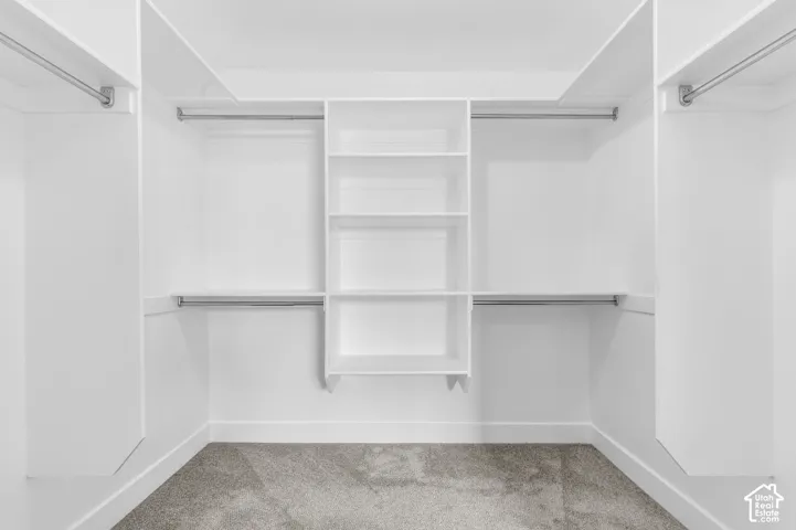Spacious walk-in closet featuring dual hanging rods, built-in shelving with multiple tiers, and concrete flooring
