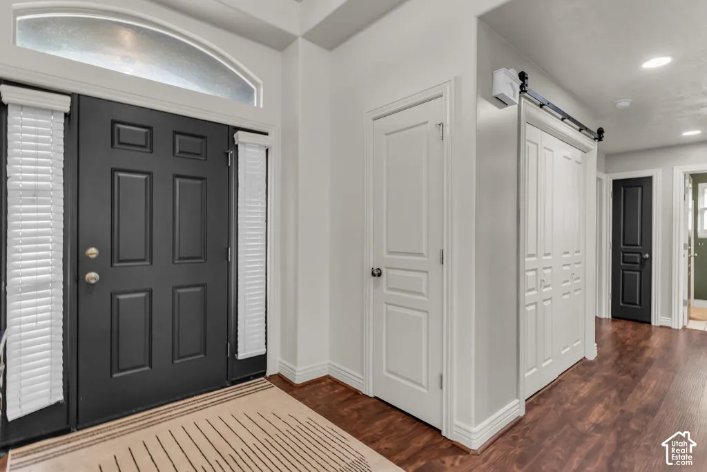 Entryway featuring a dark paneled door, decorative transom window, and wood-finish flooring