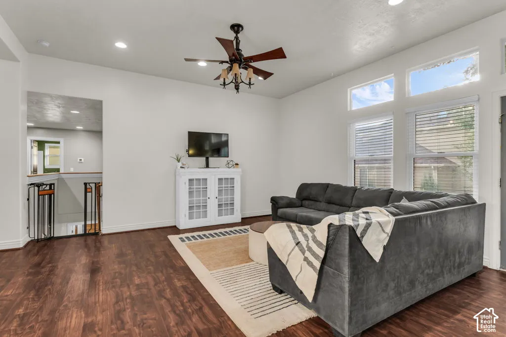 Spacious living area featuring wood-finish flooring, recessed lighting, a ceiling fan, and multiple windows providing ambient light