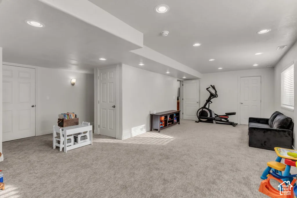 Recessed lighting, wall sconce, two panel doors, and neutral carpeting