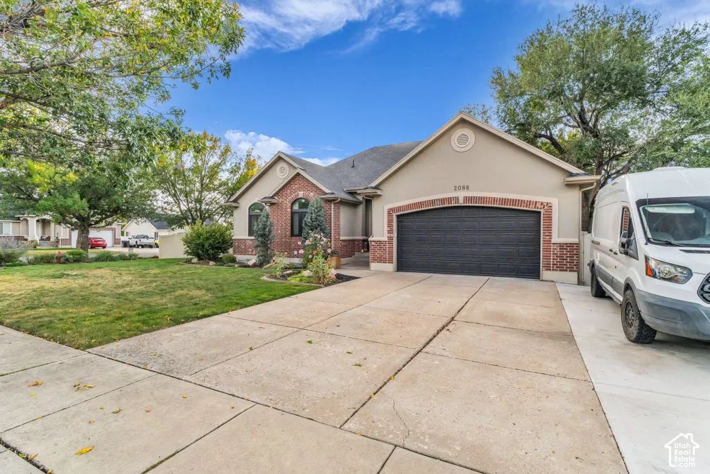 Stucco exterior with brick accents, arched windows, an attached garage, and a concrete driveway