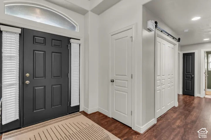 Entryway featuring a dark paneled door, decorative transom window, and wood-finish flooring